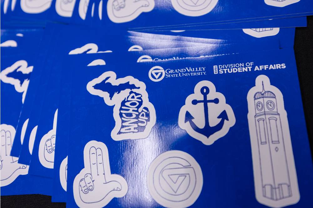 A collection of GVSU themed stickers. The state of Michigan with "Anchor Up" inside, the Laker Up sign, a blue anchor, and GVSU GV logo, and the signature GVSU clocktower